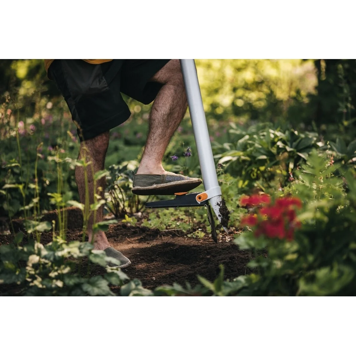 Fiskars Xact bulb planter foot pedal pressed into garden soil