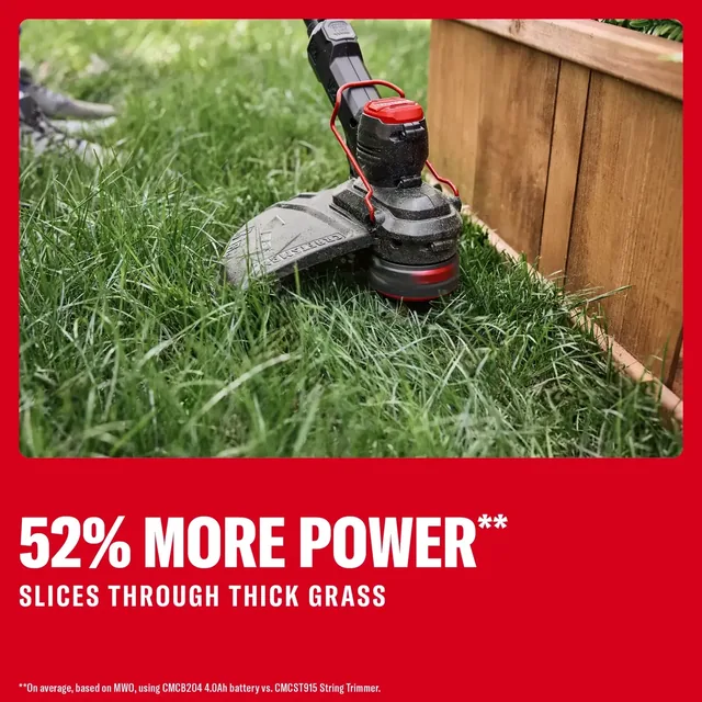 Photo of Craftsman string trimmer CMCST901M1 cutting thick grass next to a wooden garden bed.