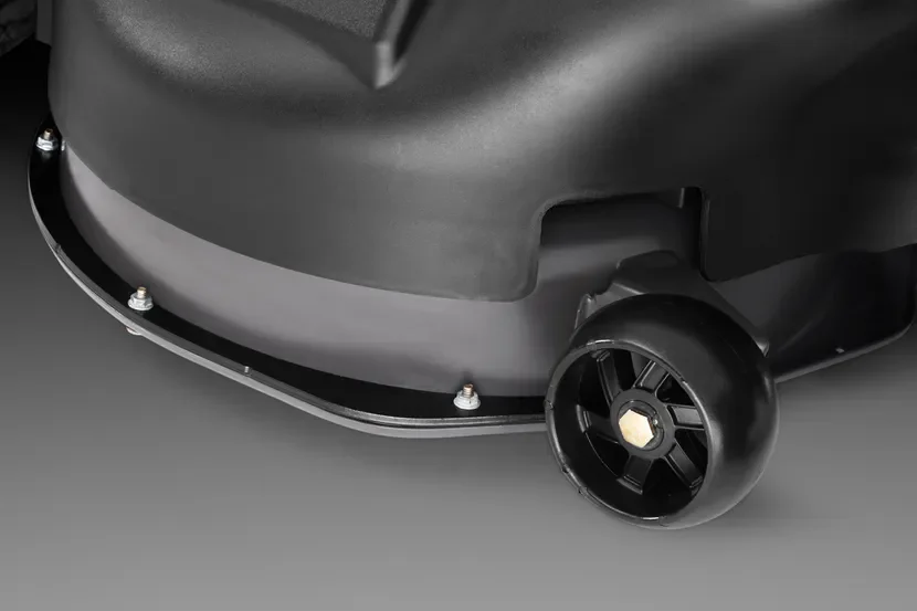 Close-up view of a lawn mower's cutting deck and wheel.